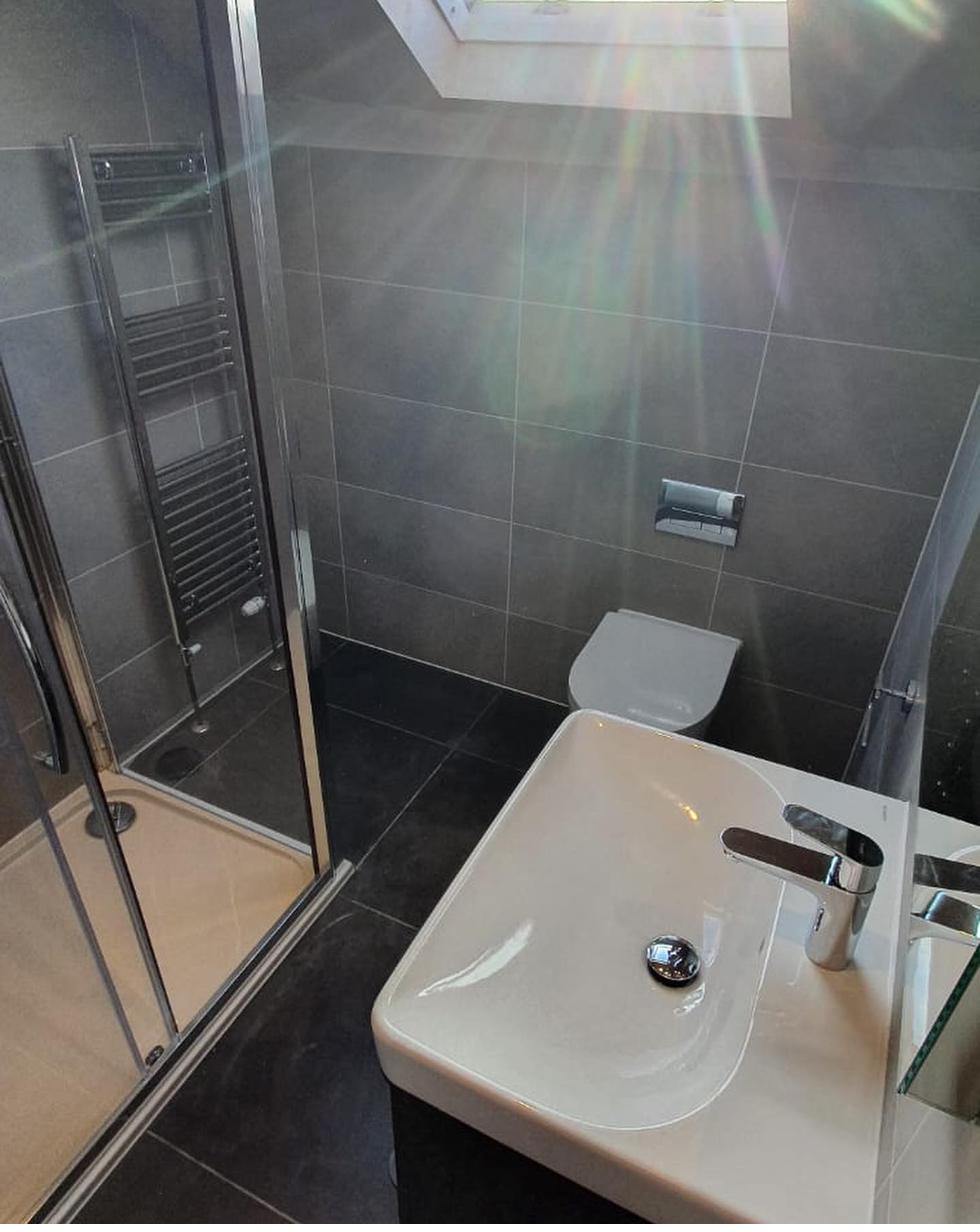 Shower room with large format grey tiles by RyBuild Ltd
