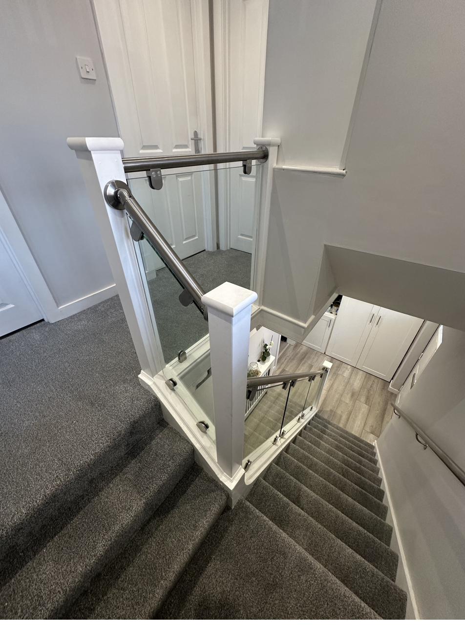 Landing with glass staircase panels by RyBuild Ltd