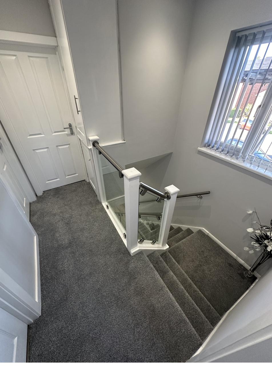 Staircase top landing view with glass balustrade by RyBuild