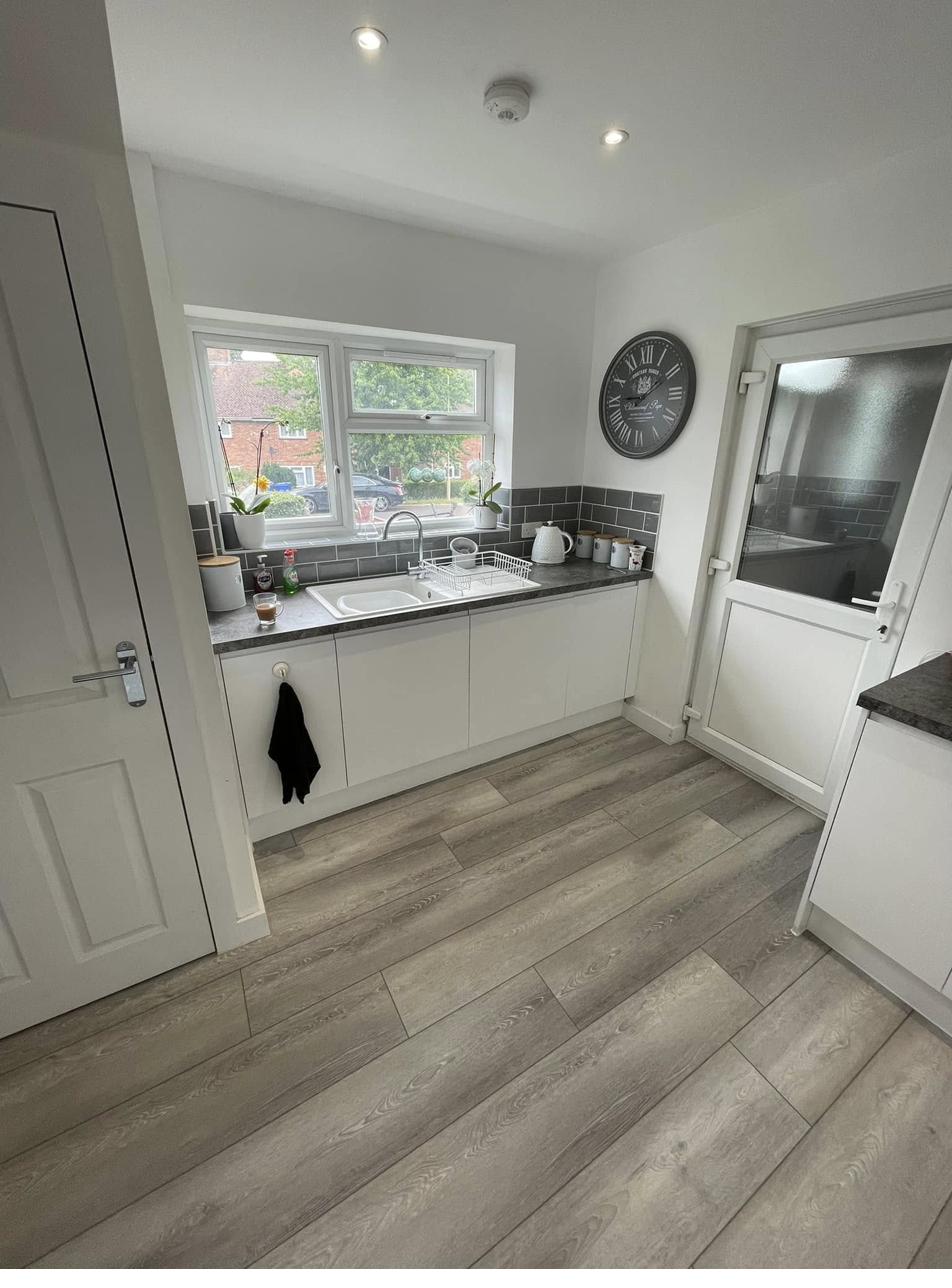 Kitchen sink area with white units and grey tile splashback